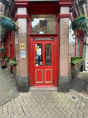 Red wooden and glass door ahead. Pull gold metal handle on left to open.
