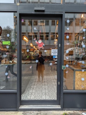 Glass door with green frame and no handle. Push button to right of door. Door slides left to open.