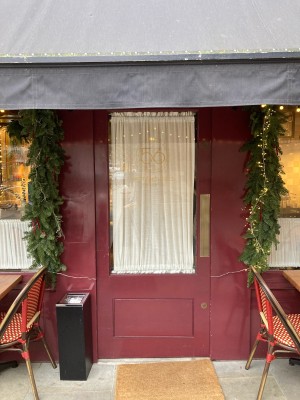 Glass door with red frame ahead. Push door to open via metal pad on right.