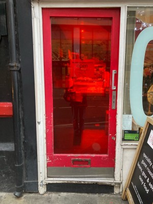 Red glass door ahead. Push door to open via handle on right.