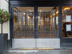 Glass doors with black frame and metal handles in centre. Pull to open.