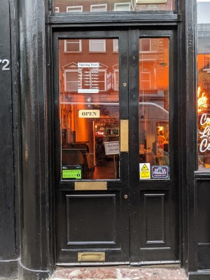 Wood and glass door with black frame. Metal handle on right, push to open.