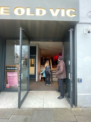 Double glass door with grey frame. Push button to right of door. Doors open outwards.
