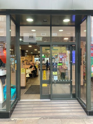 Glass doors with grey frame ahead. Left door slides to open automatically.