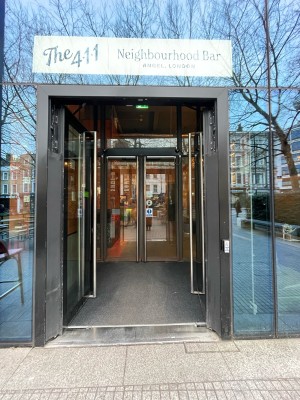Glass doors with black frames. Push metal handles in centre to open. Push button on right. Doormat following.