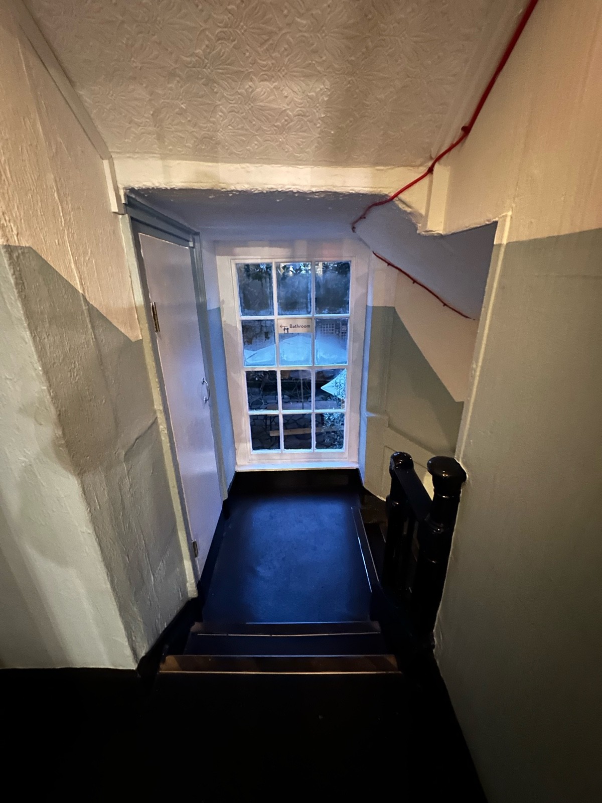 From archways facing straight. 2 steps down ahead. Black wooden handrail on right.