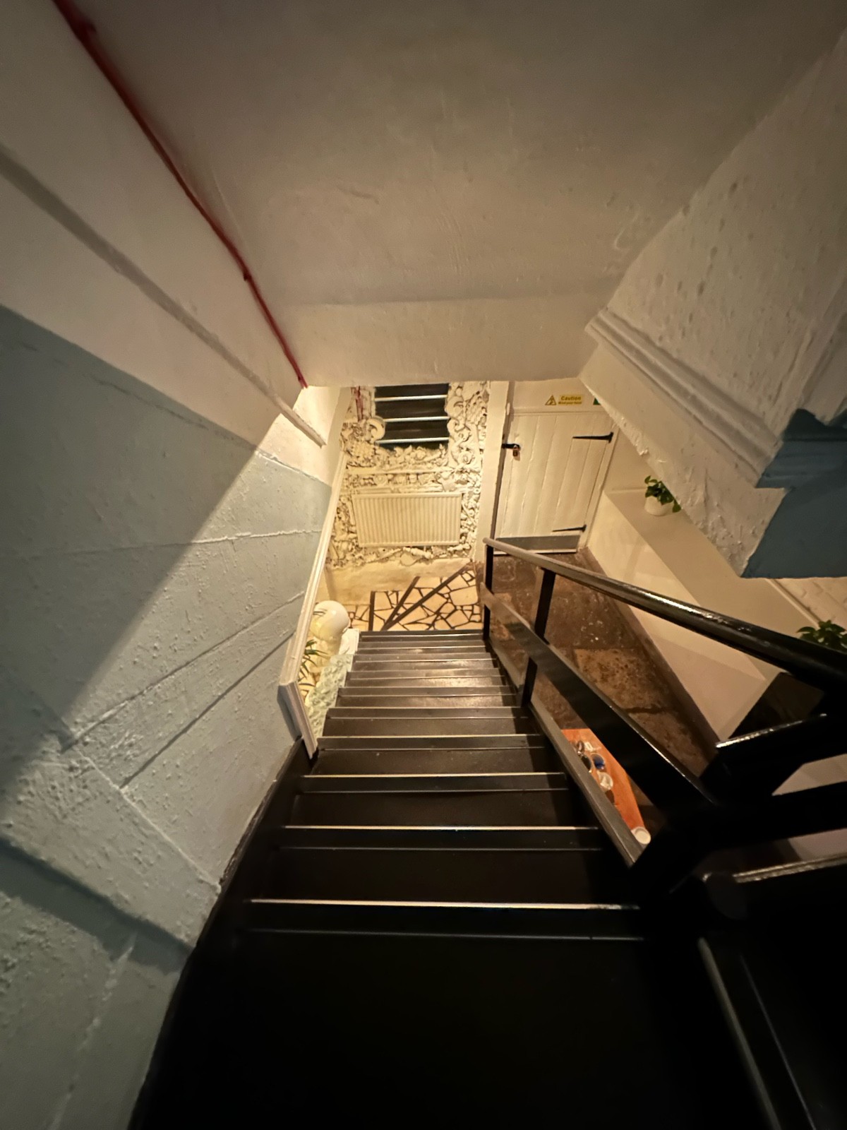 From second landing facing right. Stairs continue ahead. Black wooden handrail along right.