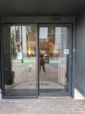 Glass door with grey frame and no handle. Slides left to open.