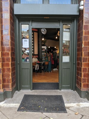 Green door with green frame. Metal handle on left side, push to open.