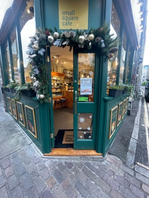 Glass doors with green wooden frame ahead. Push gold metal handles in centre to open.