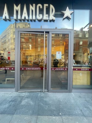 Glass doors with grey frame ahead. Push silver metal handle in centre right to open.