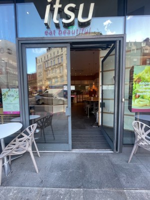 Glass doors with grey frame ahead. Push grey metal pad in centre to open.
