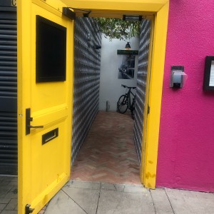 Yellow wooden door. Pull metal handle on right to open.