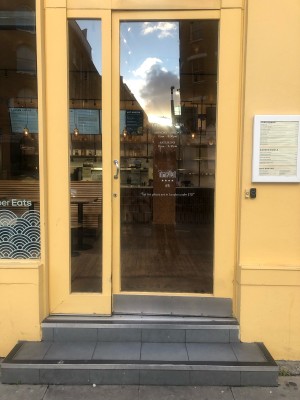 Glass panelled yellow door. Push handle on left to open. Steps up to door.