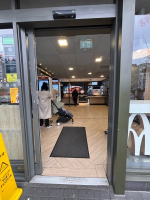 Glass door with grey frame ahead. Automatic sliding door for opening.