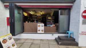 From pavement facing venue. Glass window ahead. Counter at the back.
