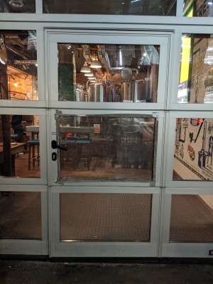 Glass door with metal frame and black handle. Pull from left to open.