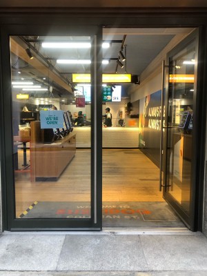 Glass doors with grey frame. Push metal handle in centre to open.