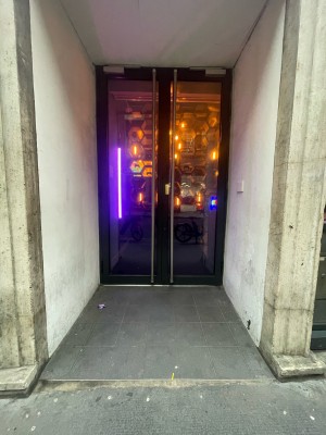 Glass doors with black frames ahead. Push silver metal handles in centre to open.