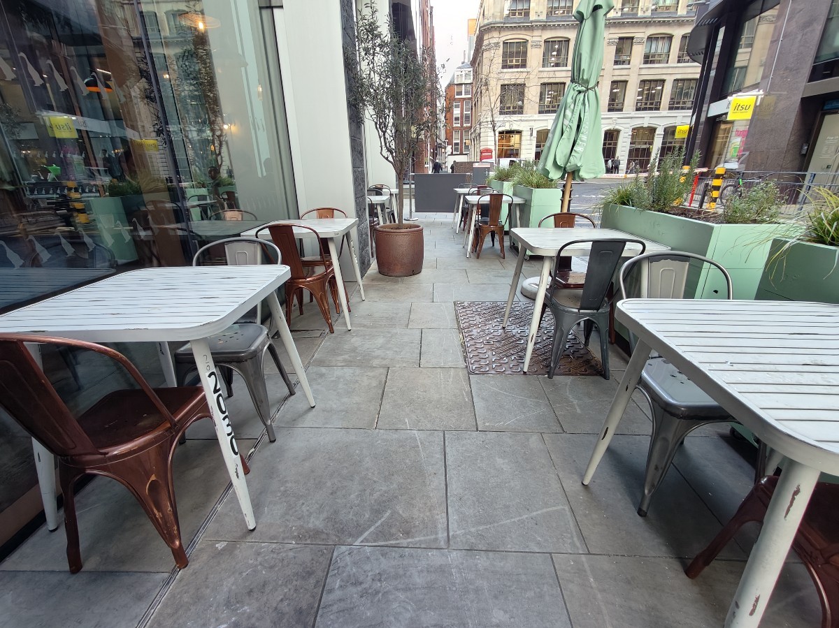 From after planters on left facing straight. Table sand chairs along both sides. Planters and parasol on back left and right obstructing path.