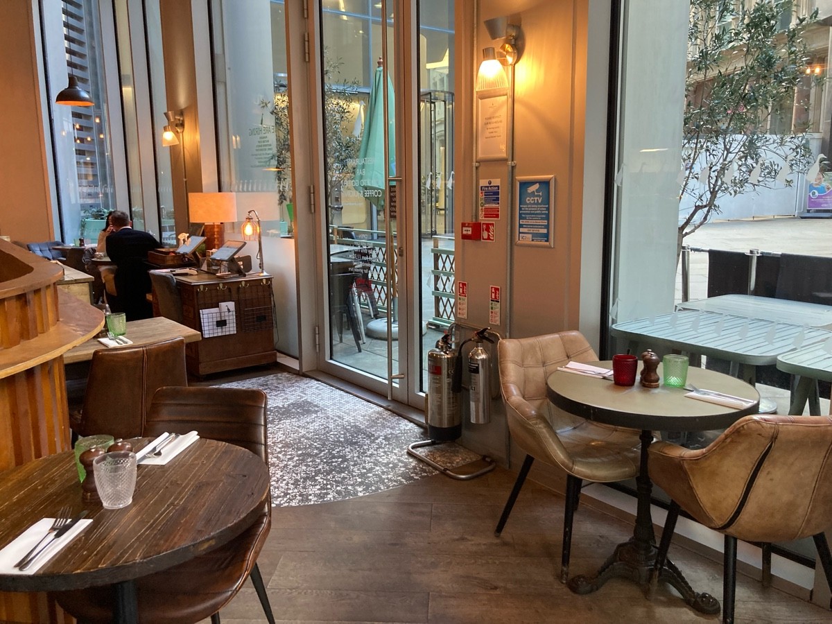 From end of divider, facing left. Tables and chairs on both sides. Alternative entrance on back right. Alternative welcome desk behind.