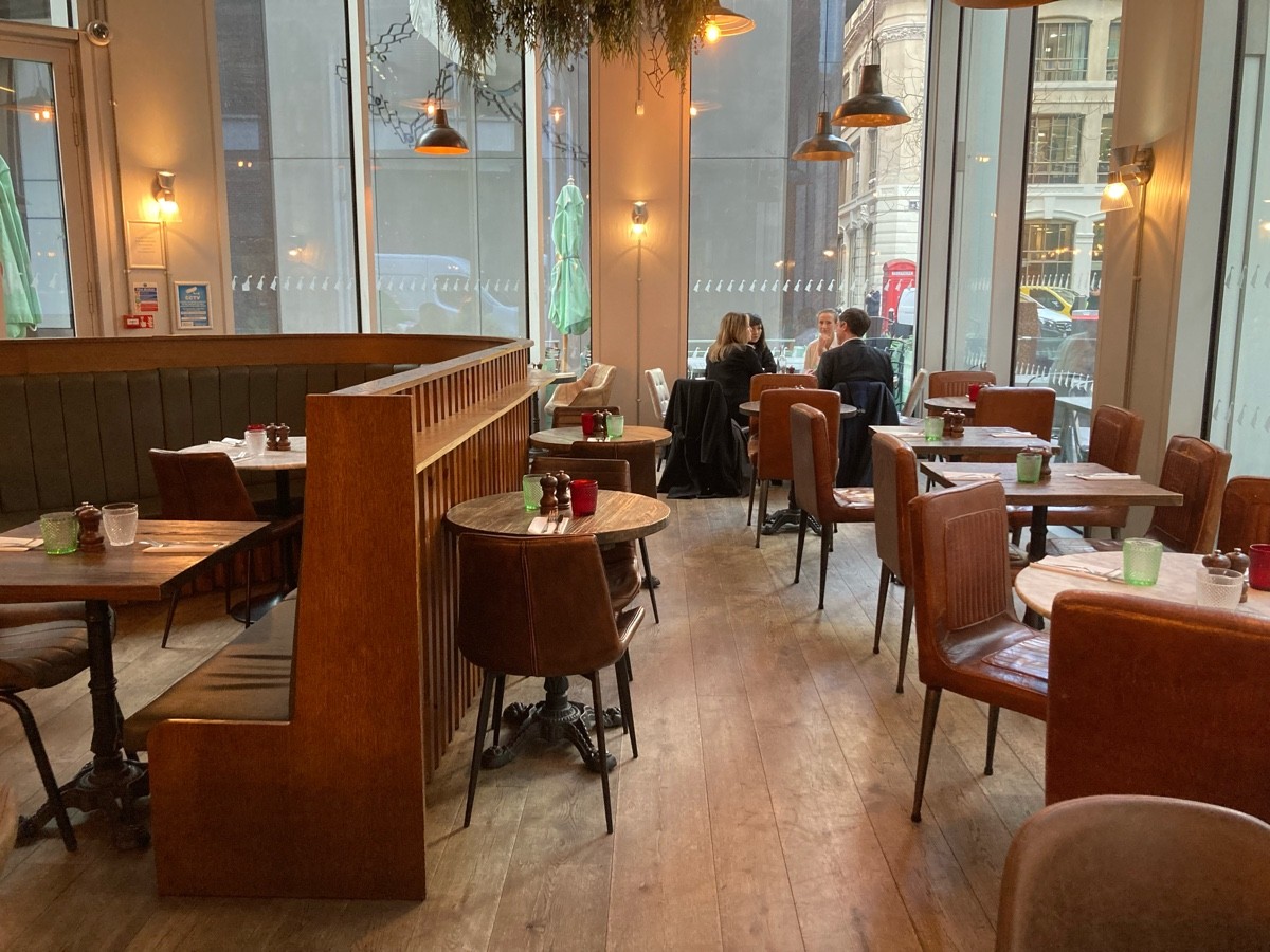 From end of railing, facing straight. Tables and chairs along right. Tables and chairs along divider on left.