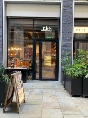 Opening ahead to door on back. A-framed sign on left, outdoor counter behind. Planters along right.