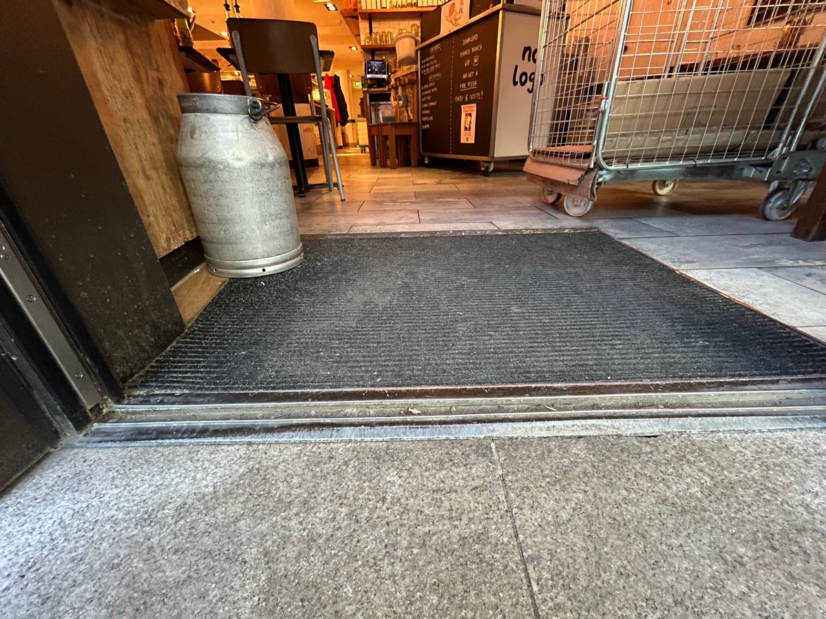 Small bump at foot of door. Doormat following. Small bump at end of mat.