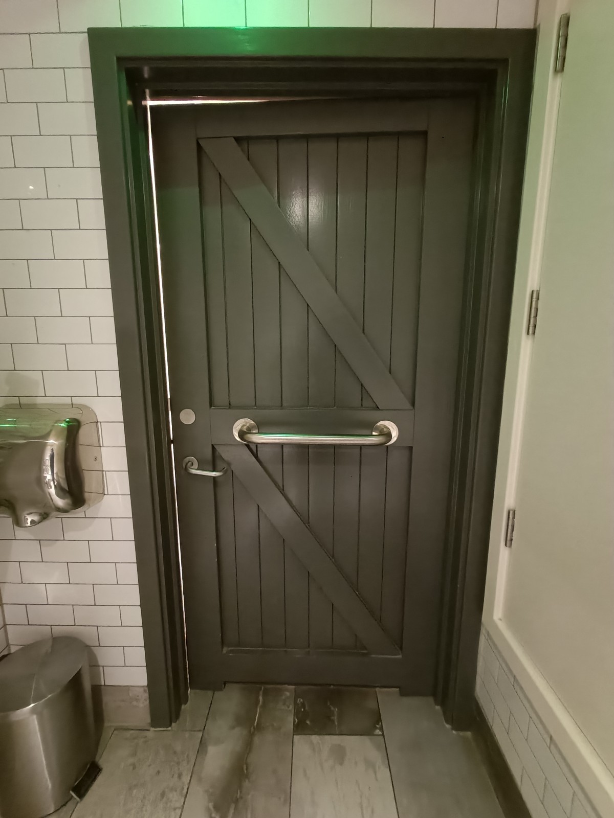 Back of bathroom door. Silver, metal grabrail in middle. Silver, metal lock on left.