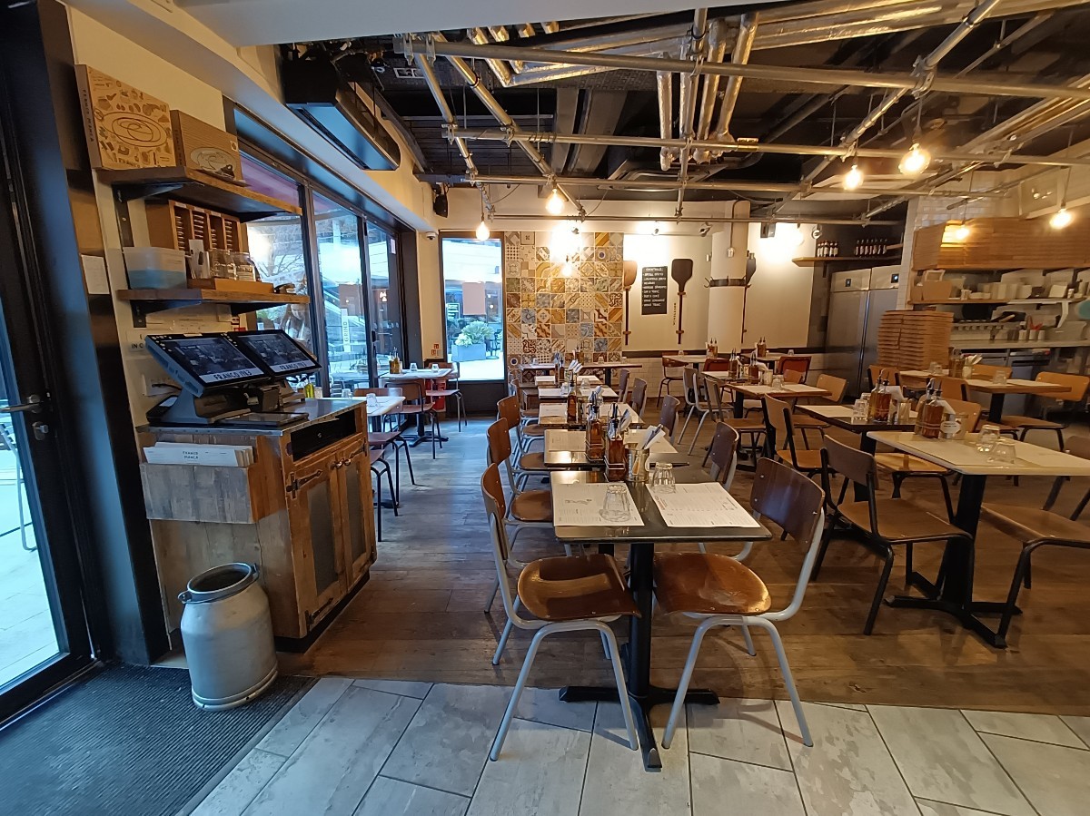 From entrance, looking left. Service counter on left. Rows of tables and chairs spread ahead.