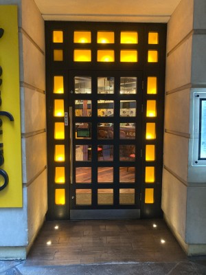 Opening ahead to entrance door on back. Glass door with black frame. Pull door to open via handle on left.