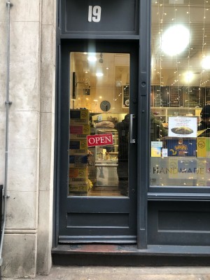 Glass door with grey frame. Pull on metal handle on right to open.
