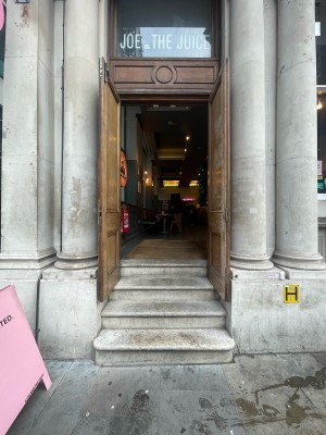 Brown wooden doors ahead. Steps up before door. Assistance button to right of doors.