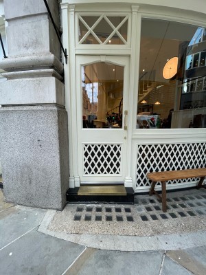 White wood-panelled glass door. Push brass handle on right to open.
