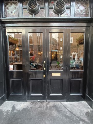 Glass door with black frame. Pull golden, metal handle in middle to open.