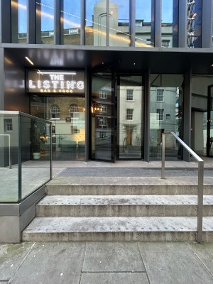 Steps up to entrance at back with silver handrails along left and right. Ramp up to entrance on left.