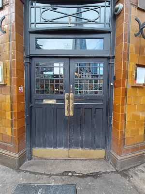 Grey door with glass panels. Push golden, metal pads in middle to open.