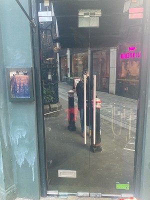 Glass doors with black frame ahead. Pull door to open via metal handle in center.