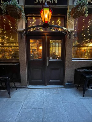 From street facing venue. Wood-panelled door ahead. No handles. Push at centre to open.