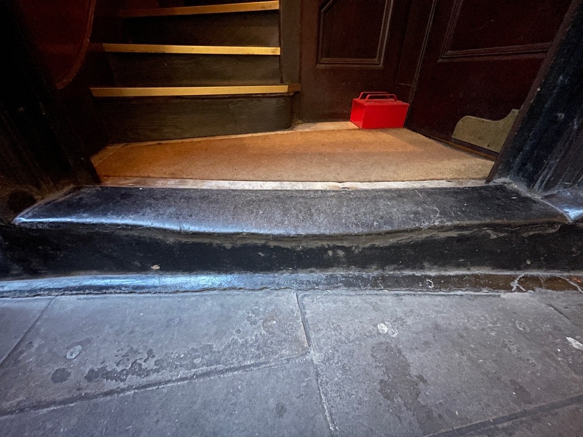 One step up before archway. Black step with curved edge. Doormat immediately after archway.