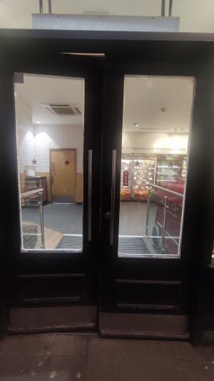 Glass doors with black frames. Push metal handles in centre to open.