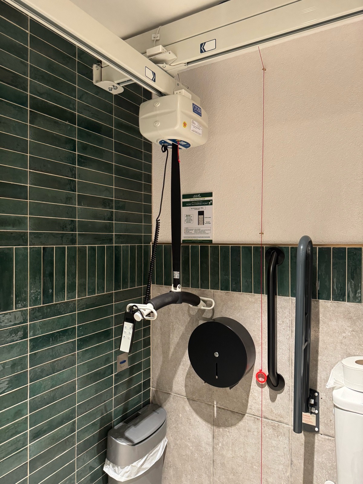 Hoist charger is in top left corner of the room next to the toilet