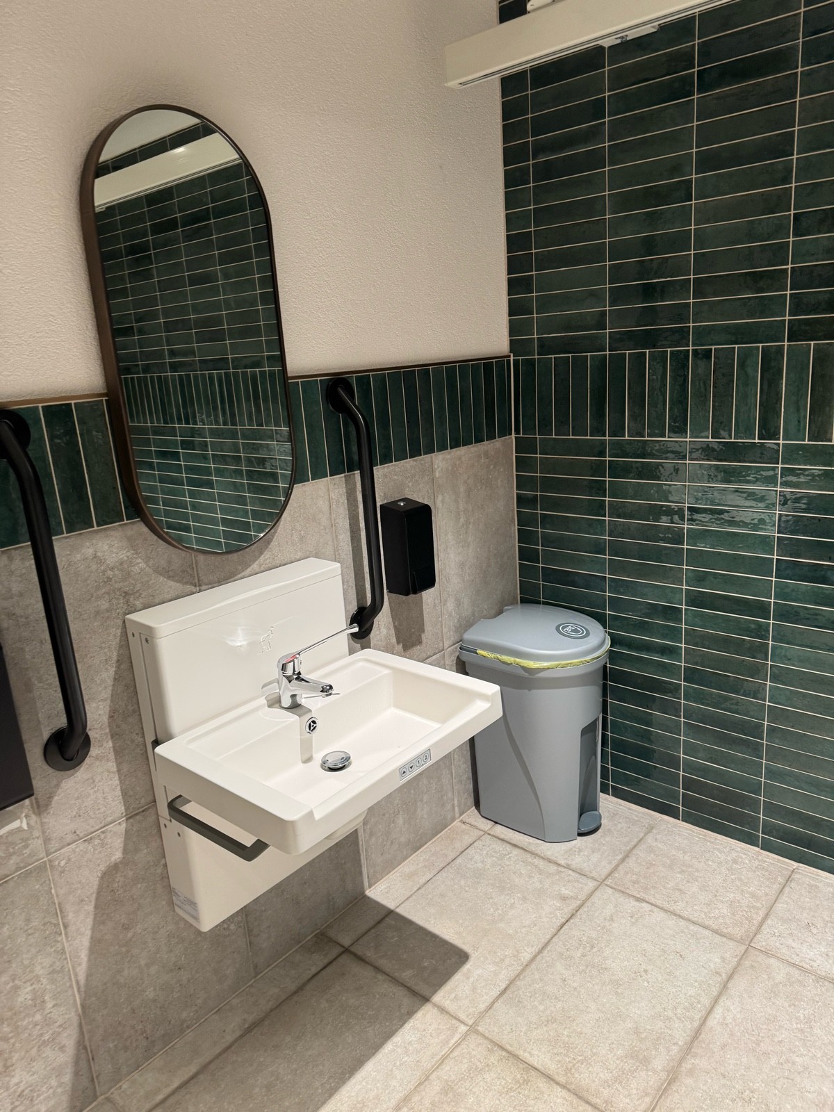 Height adjustable sink soap dispenser on right paper towels on left and foot pedal nappy bin on the right