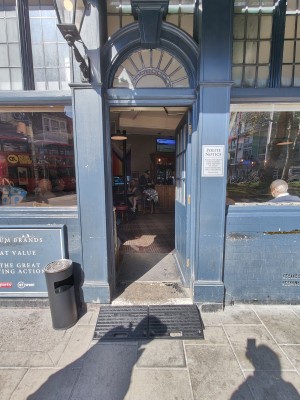 Ramp upon request to blue framed glass door. Push from left to open.