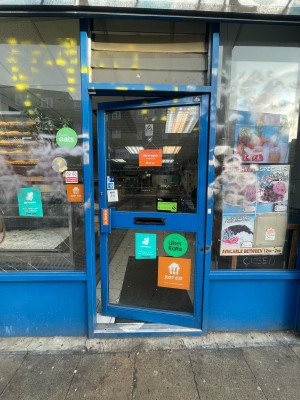 Glass door with blue frame ahead. Push blue metal handle on left to open.