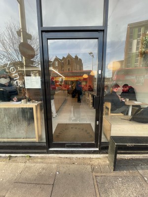 Glass door with black frame ahead. Push black metal handle on right to open.