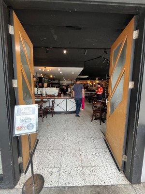 Brown wooden doors with opaque glass panels. Push from middle. Signage obstructing on left.