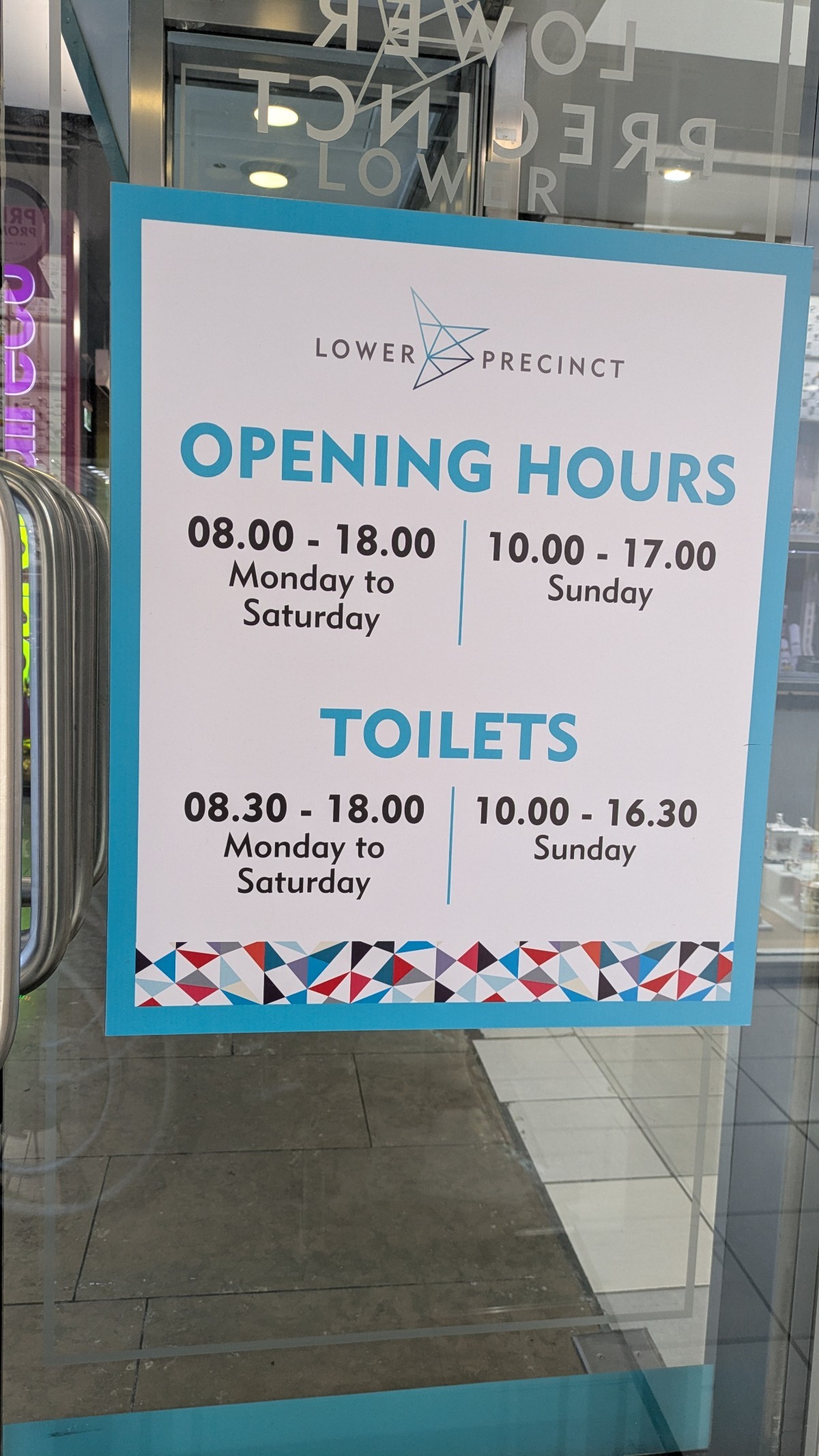 A sign showing the opening times of shops & toilets. Bathrooms close earlier than the stores each day. Good size/ contrast/ font used in brand colours