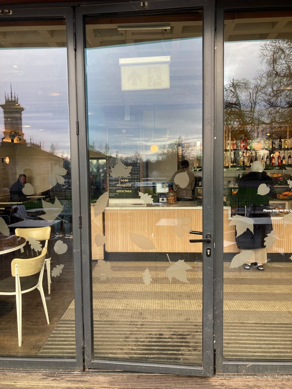 From midway of path, facing right. Glass door with black frame ahead. Pull from right to open.