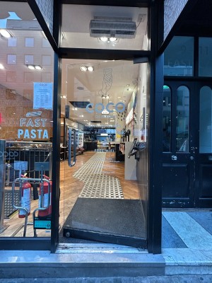 Glass door with silver handle on left ahead. Push to open.